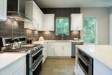 Bright modern kitchen with white cabinets, gray tile backsplash, and stainless steel appliances