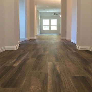 Empty hallway with dark wood floors and a bright window at the far end