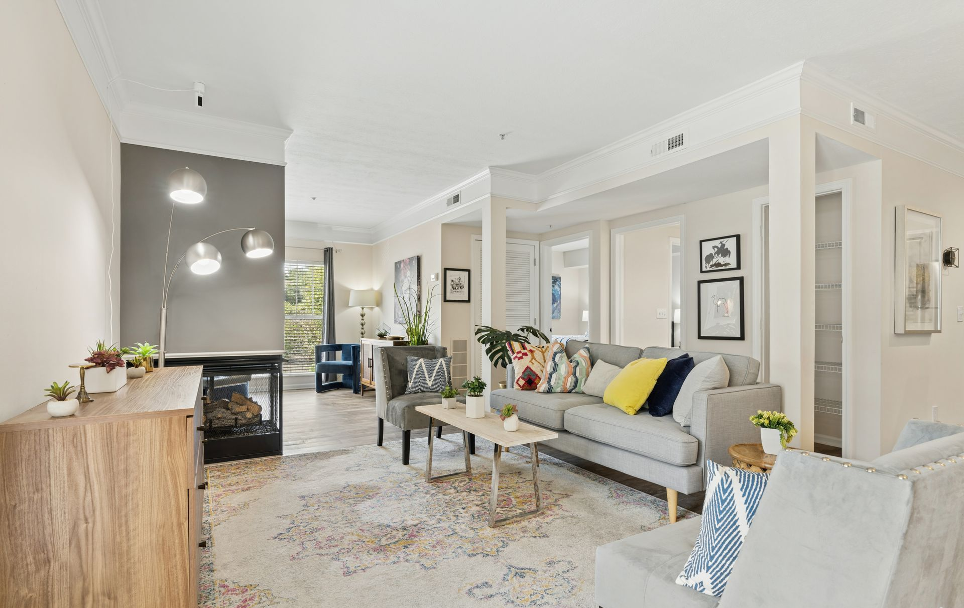 Bright modern living room with gray sofa, fireplace, coffee table, and large windows.