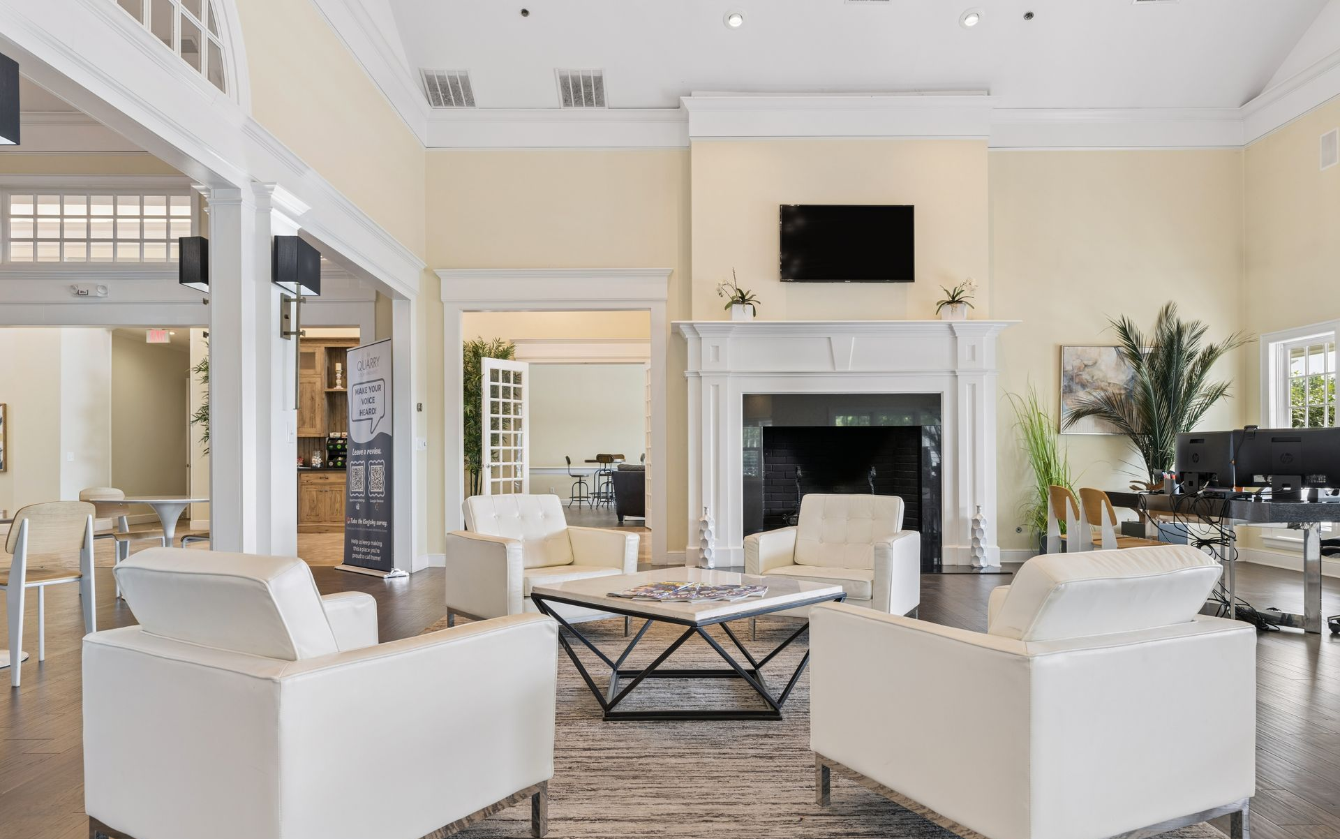 Bright, modern hotel lobby with white armchairs, a fireplace, and a high ceiling.