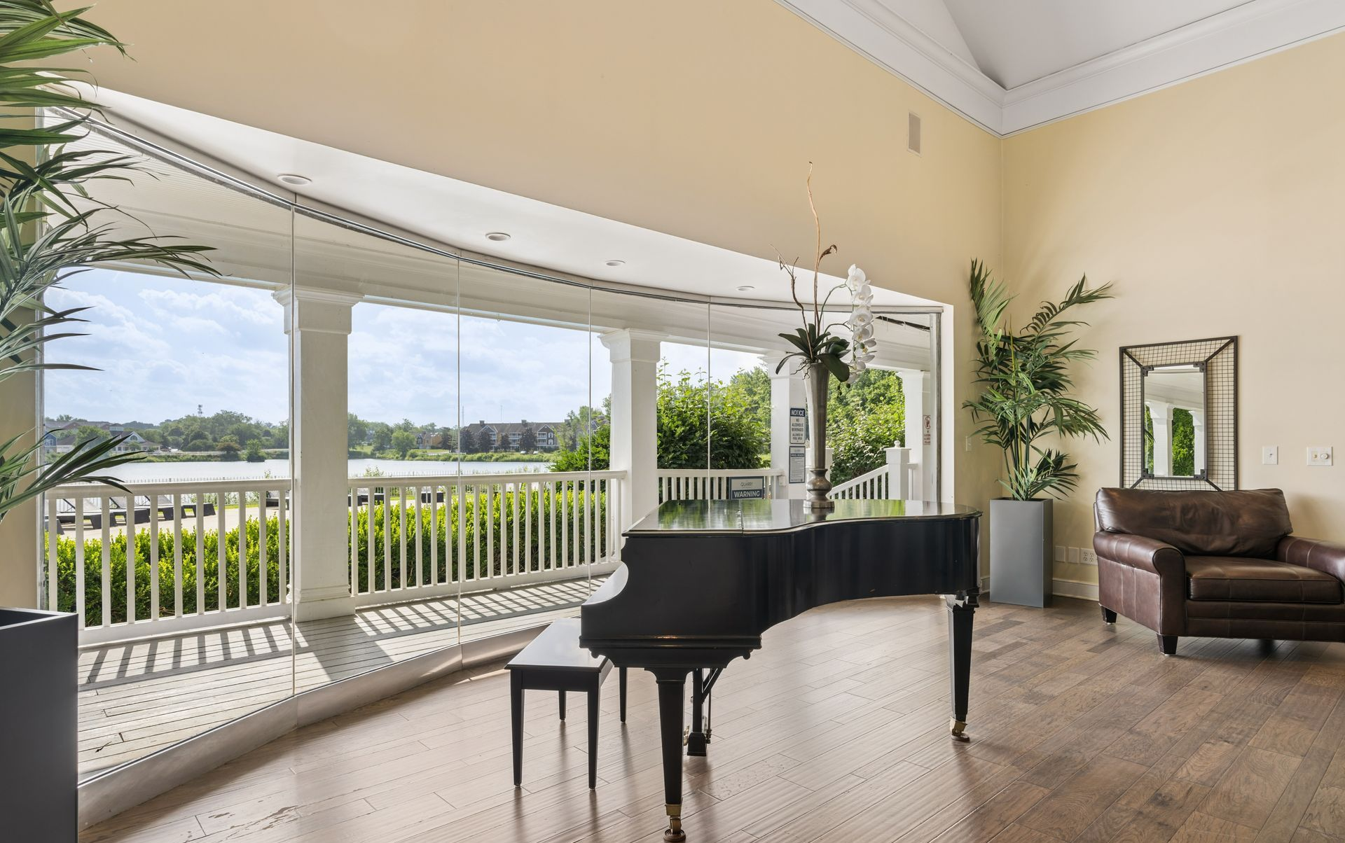 Bright living room with a grand piano, large windows, and a view of the water outside.