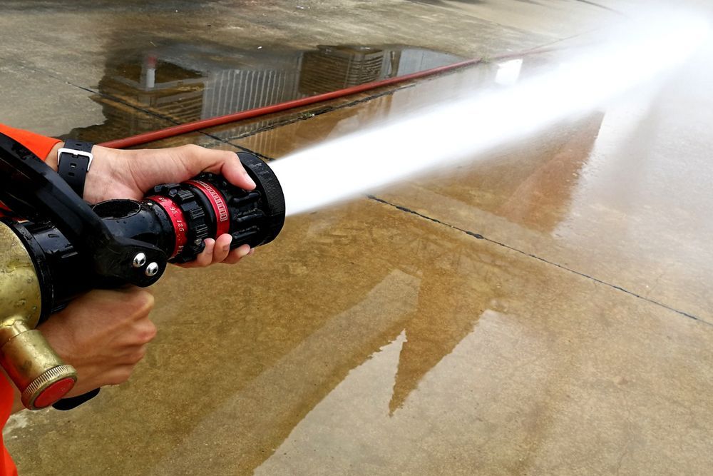 Firefighter's Hands Holding a Water Hose, Spraying a Powerful Stream — Industry Fire Services in Airlie Beach, QLD