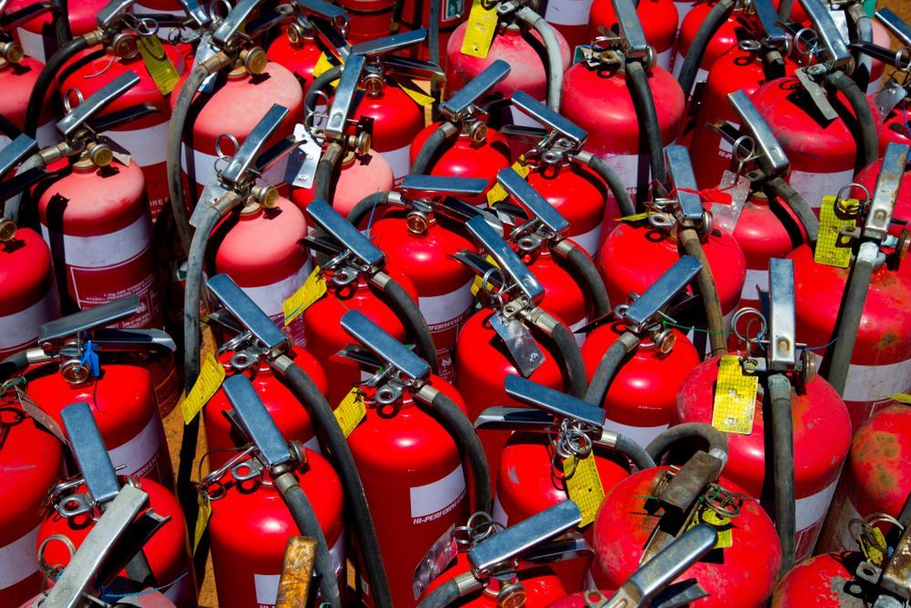 Close-up View of Numerous Red Fire Extinguishers With Silver Levers and Hoses — Industry Fire Services in Ingham, QLD