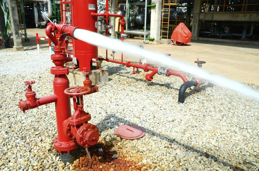 Red Fire Hydrant Spraying Water at an Industrial Site — Industry Fire Services in Sunshine Coast, QLD