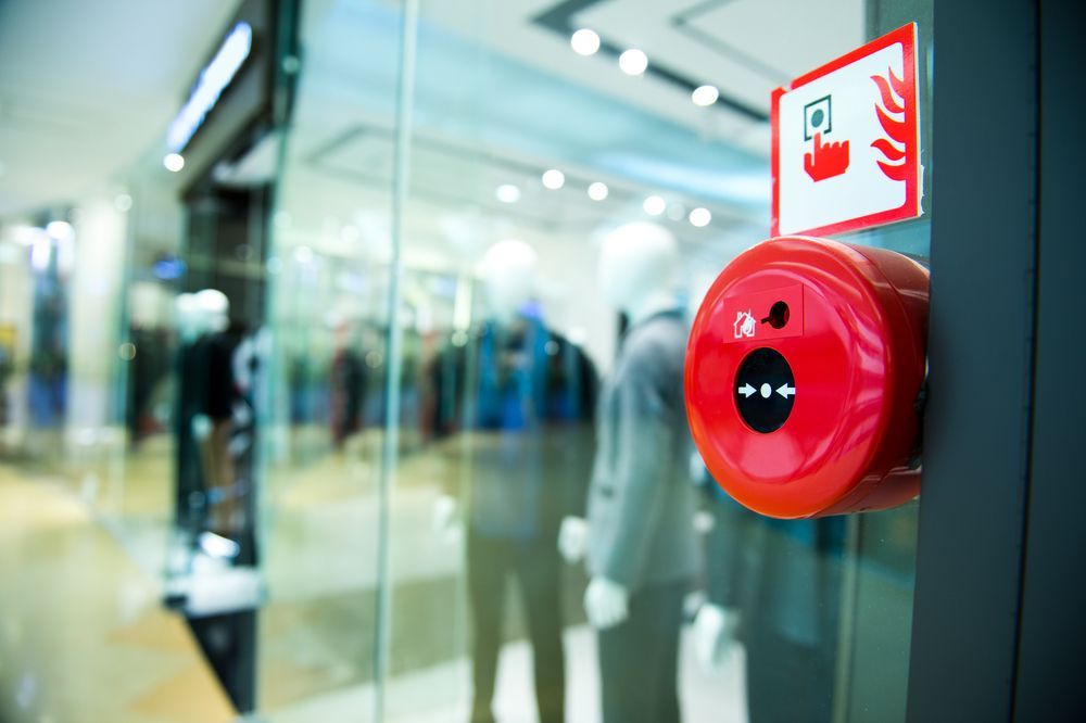 Red Fire Alarm Pull Station Next to a Storefront Window in a Retail Setting — Industry Fire Services in Cairns, QLD