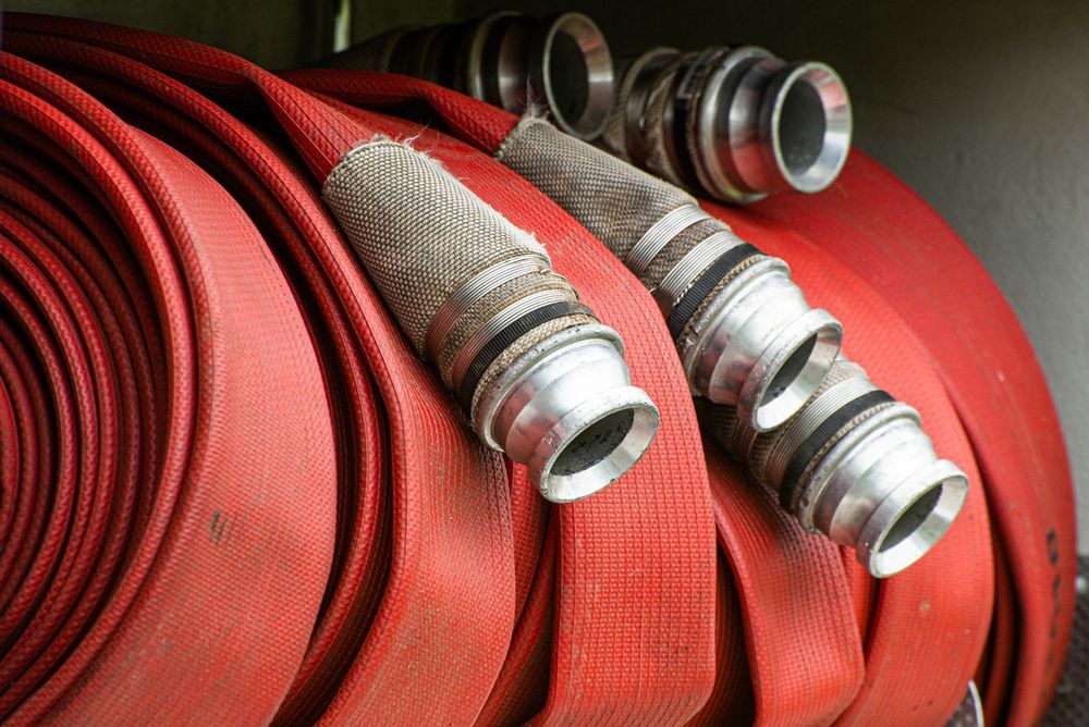 Red Fire Hose Rolled Up, With Silver Connectors Visible — Industry Fire Services in Townsville, QLD