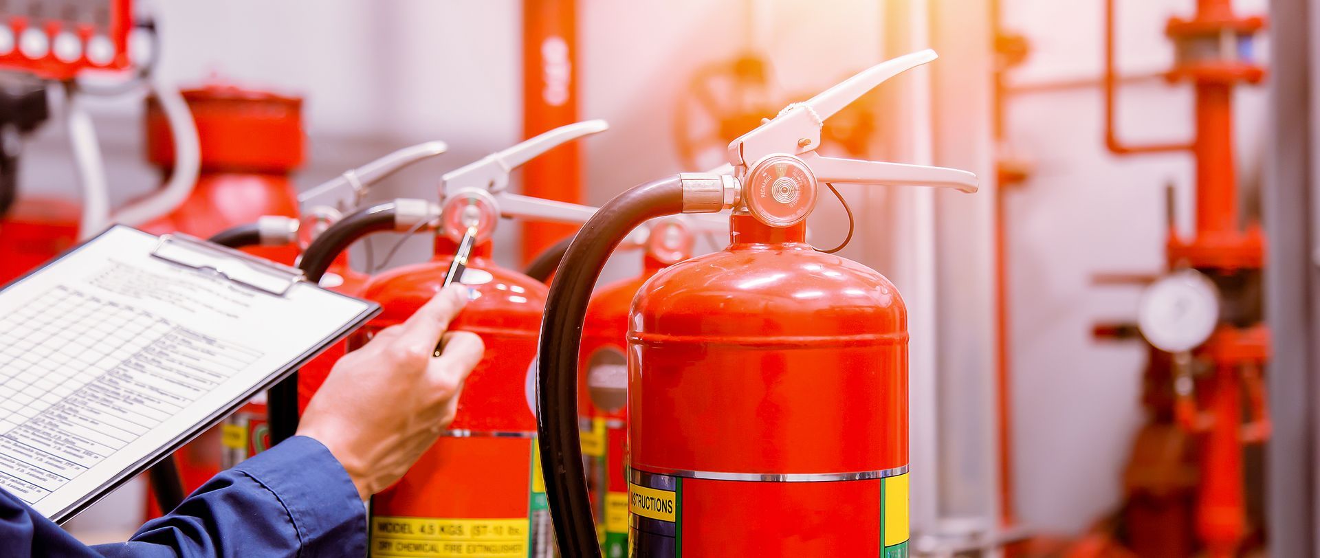 Person Inspecting Fire Extinguishers With a Clipboard in an Industrial Setting — Industry Fire Services in Proserpine, QLD
