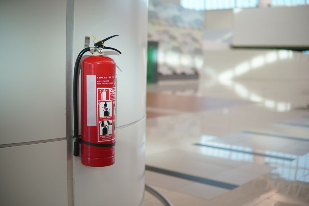 Red Fire Extinguisher Mounted on a Wall in a Brightly Lit, Modern Hallway — Industry Fire Services in Cape York, QLD