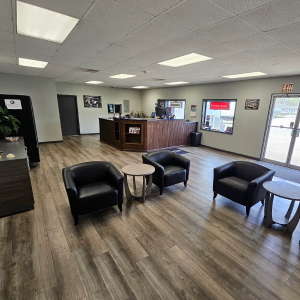 Waiting area with black armchairs, small tables, and a reception desk in an automotive shop. | Z-1 Automotive, Inc.