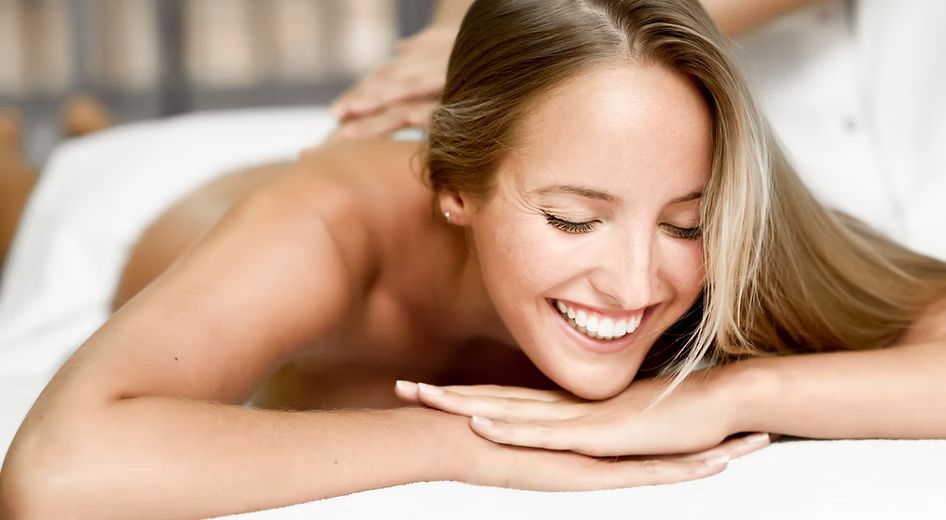 A woman is smiling while getting a massage at a spa.