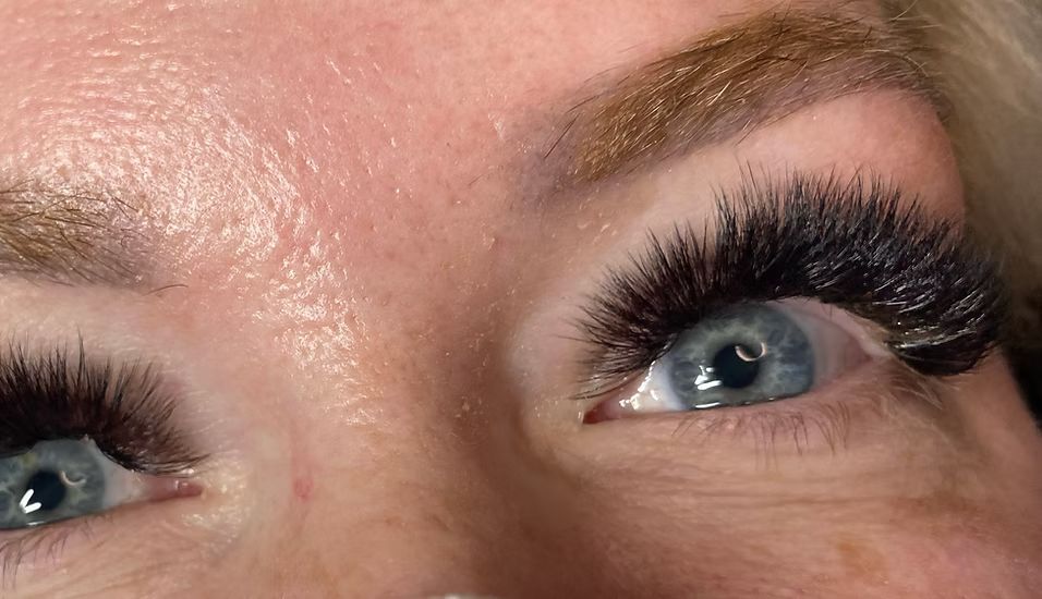 A close up of a woman 's eye with long eyelashes.