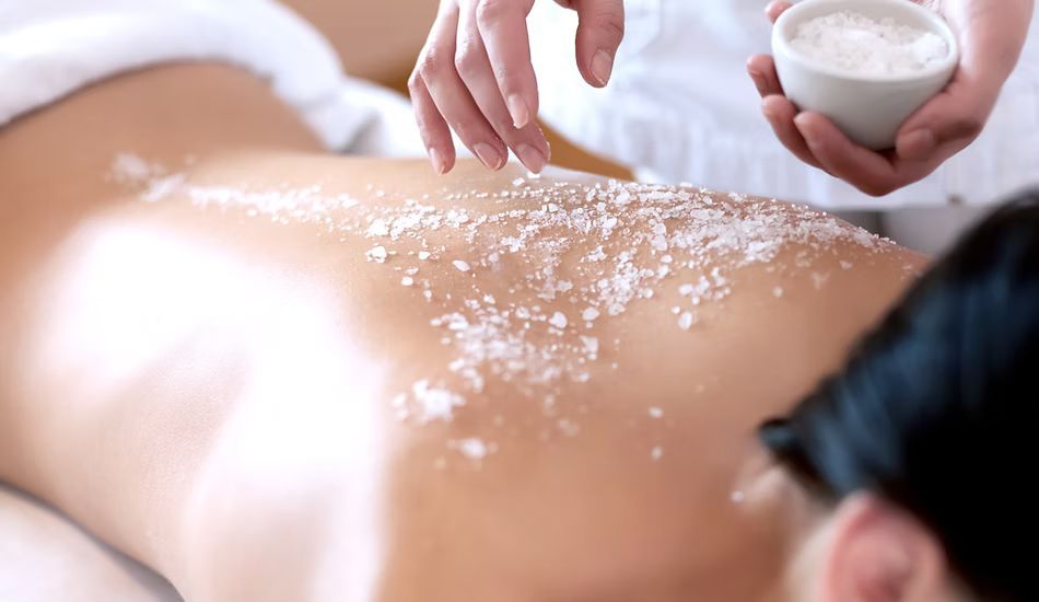 A woman is getting a massage with sea salt on her back.