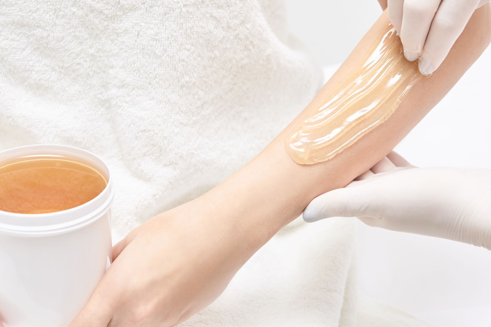 A woman is getting her arm waxed by a professional.