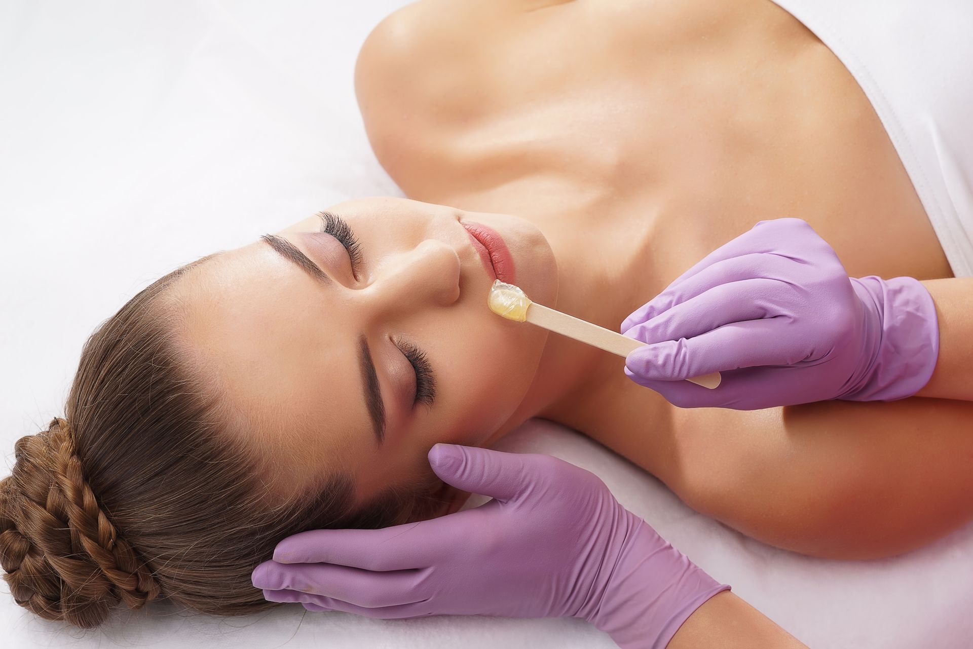 A woman is getting her lips waxed in a beauty salon.