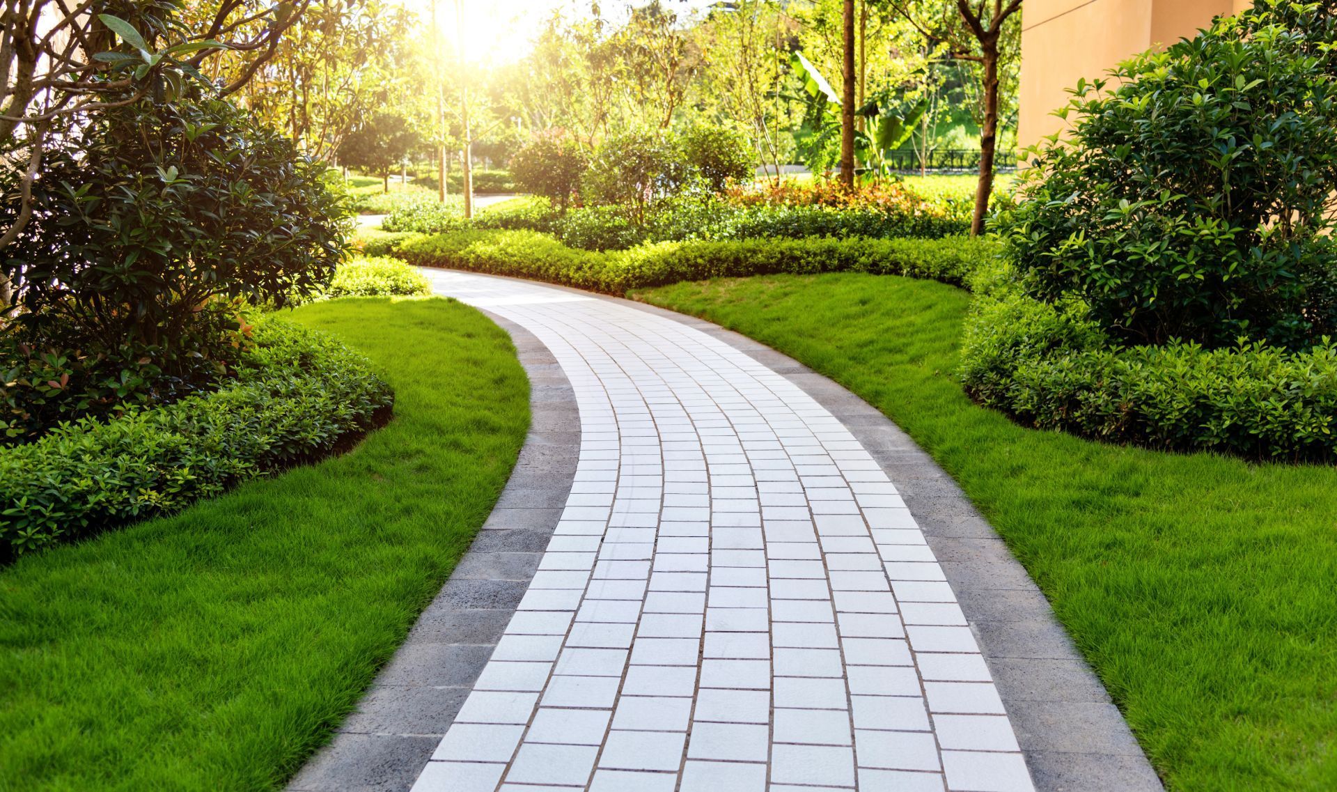 A brick walkway in a park surrounded by grass and trees.