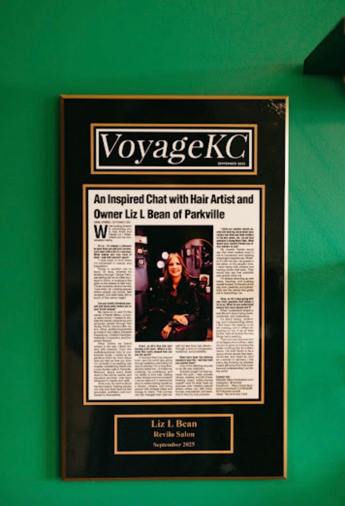 Framed VoyageKC magazine cover on green wall, featuring a central portrait and article layout.