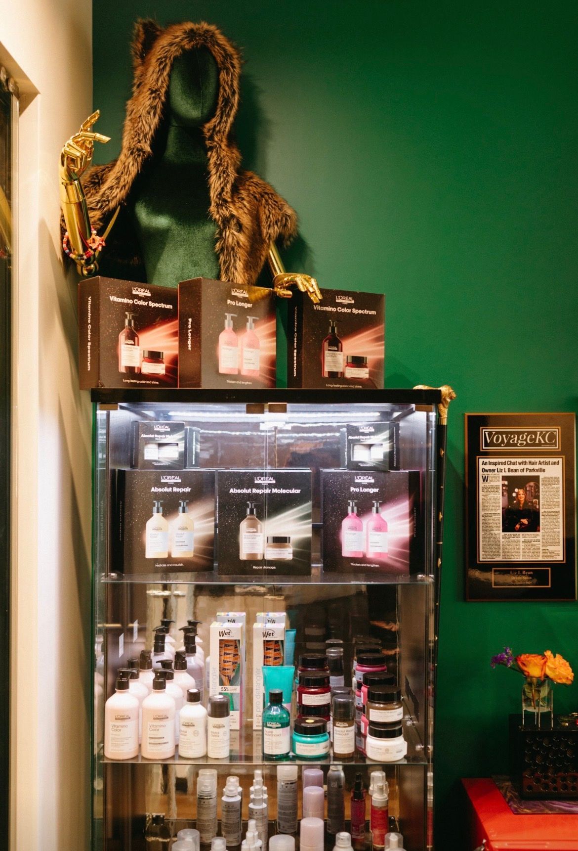 Store display with glass cabinet, shelves of products, and decorative rope on a green wall.