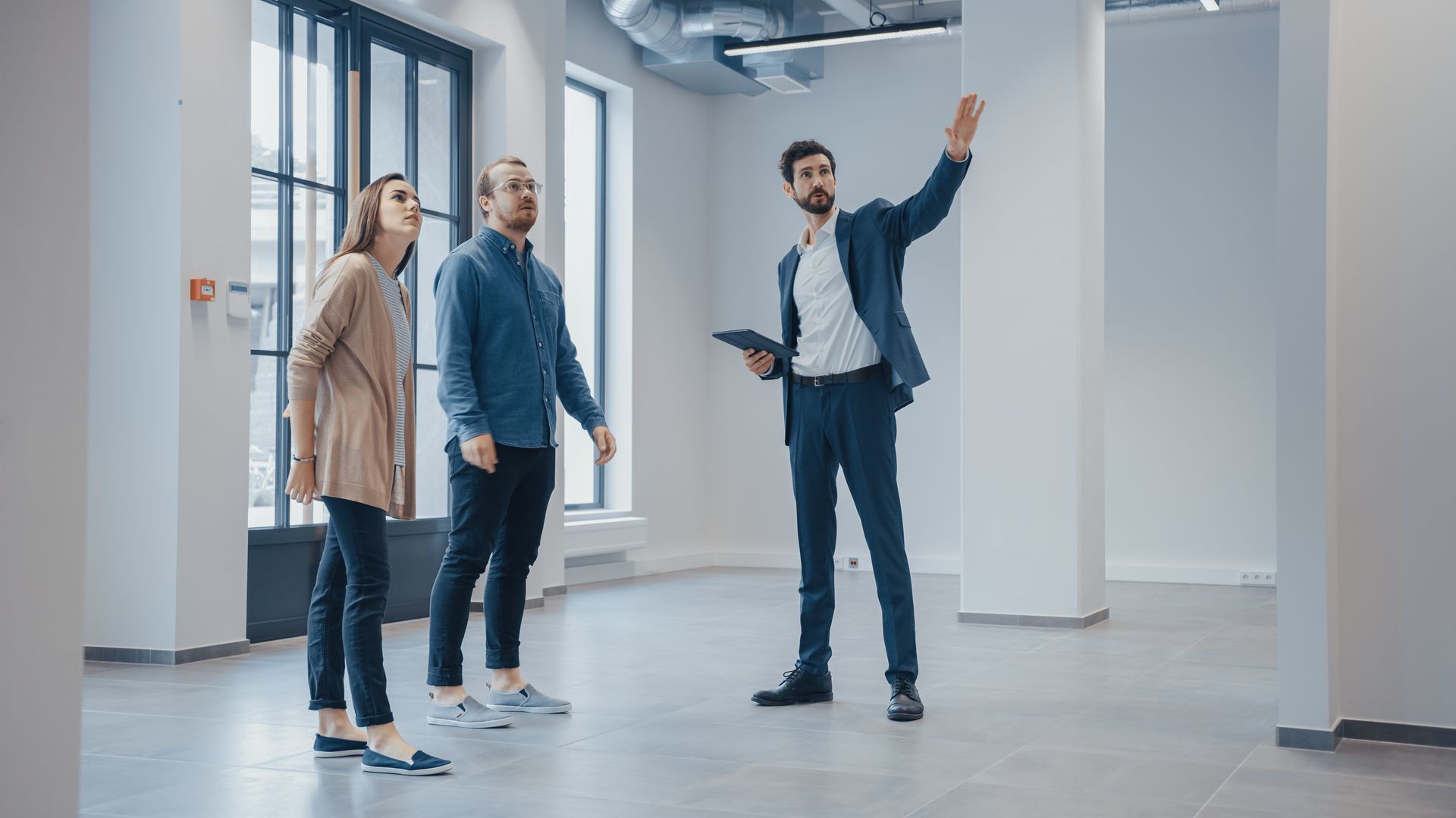 Agent showing an empty commercial space to two people during a walkthrough. Agent showing an empty commercial space to two people during a walkthrough.
