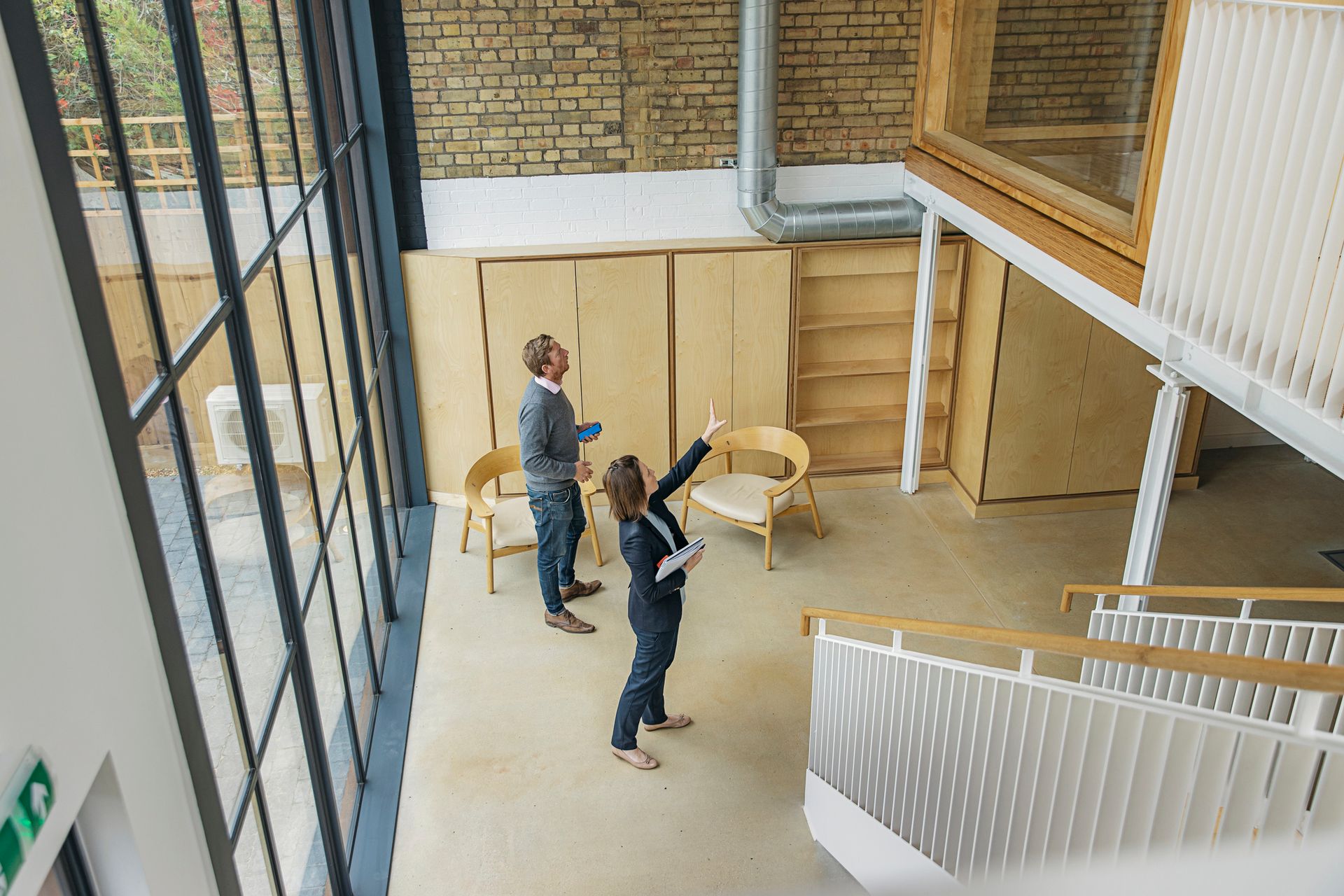 Two professionals inspecting a modern building with large windows, representing commercial real esta