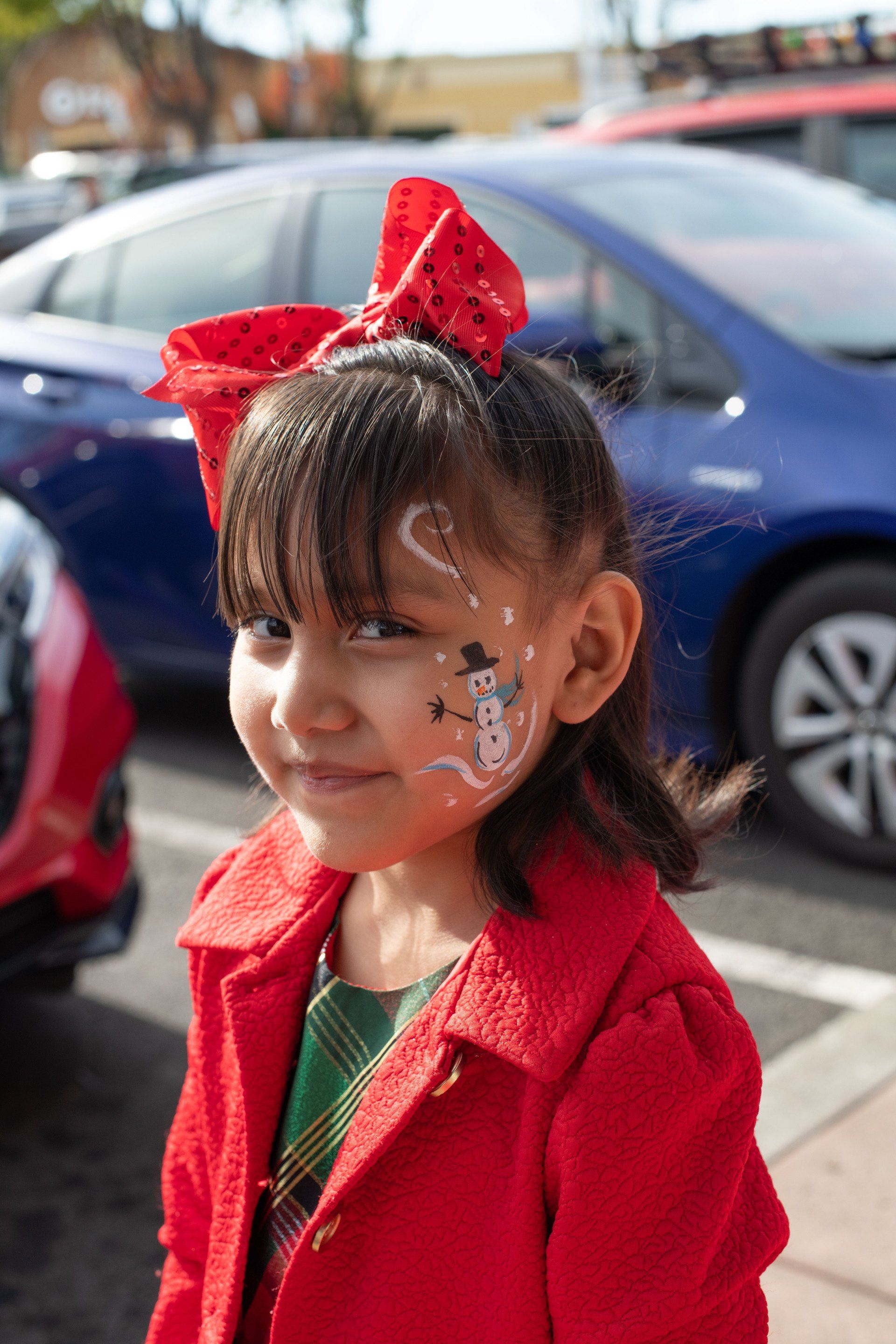A little girl with a snowman painted on her face.