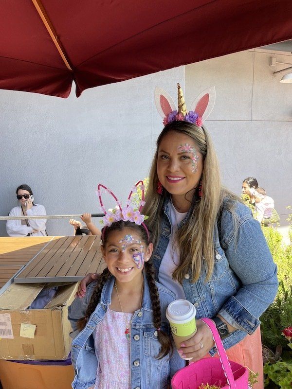 A woman and a little girl are posing for a picture . the little girl is wearing a unicorn headband.
