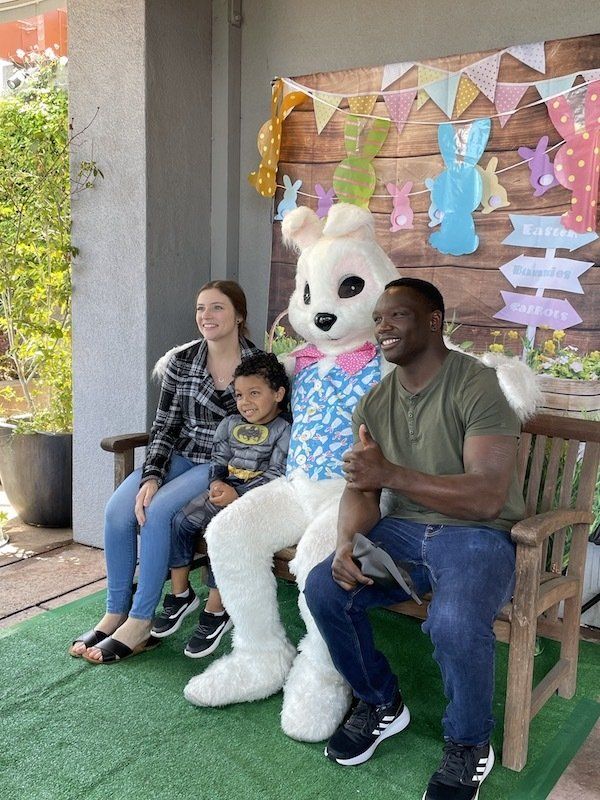 A family is sitting on a bench with a bunny mascot.