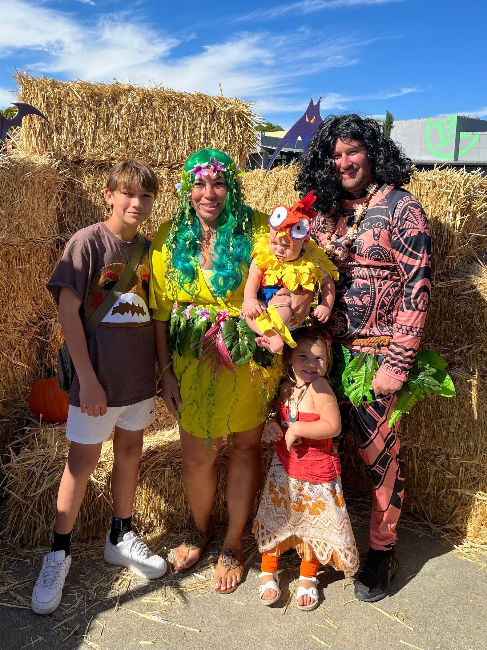 A family is posing for a picture in front of hay bales.