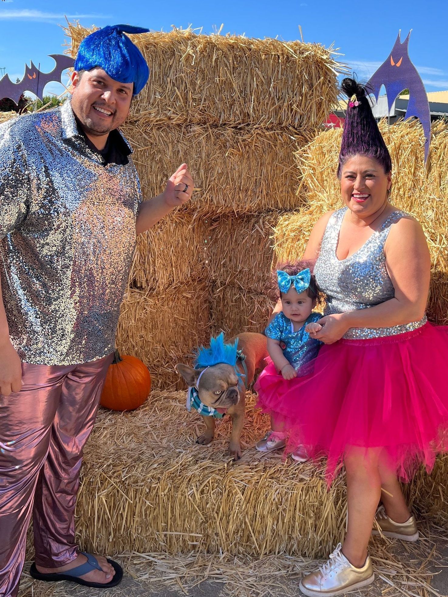 A family is posing for a picture in front of hay bales.