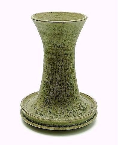 Groene keramische vaas met een uitlopende bovenkant en ronde voet op een effen achtergrond.