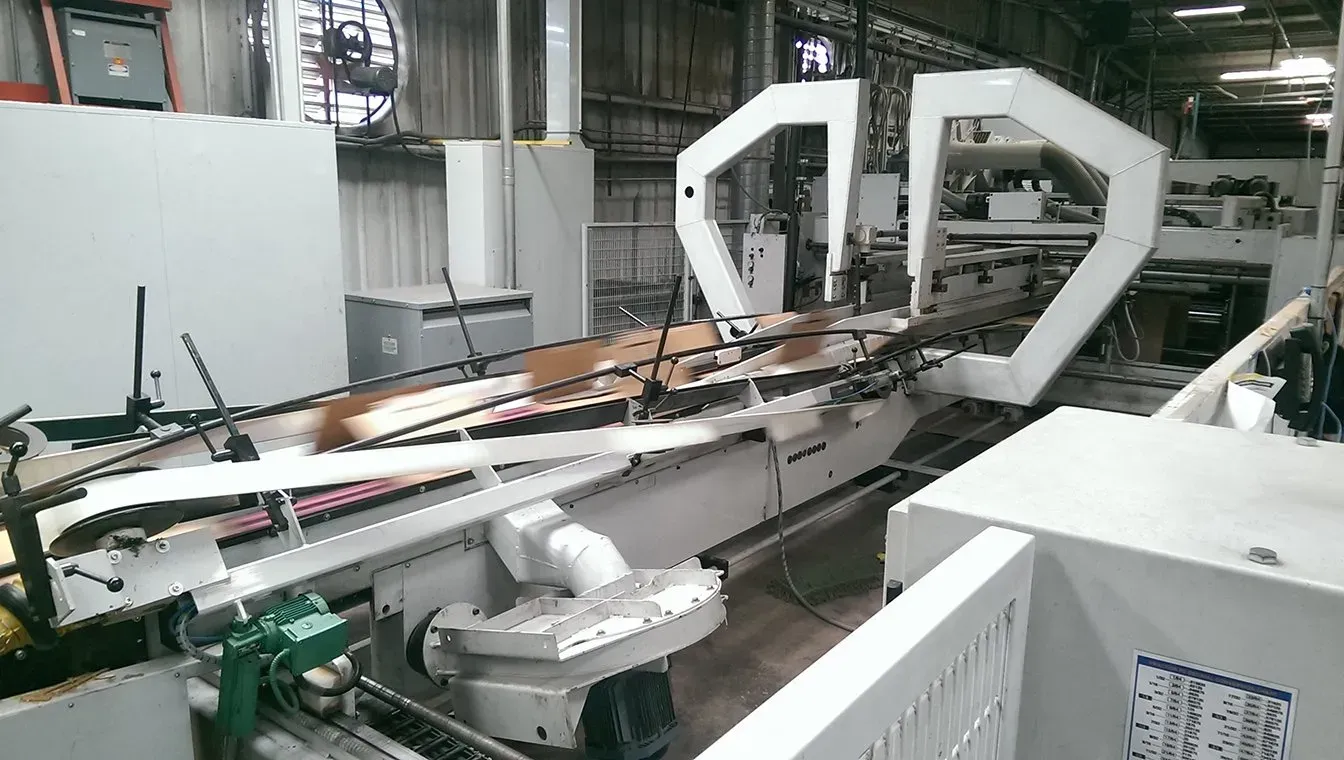 Industrial machine in a factory, with metal arms and conveyor-like equipment in a large workshop.