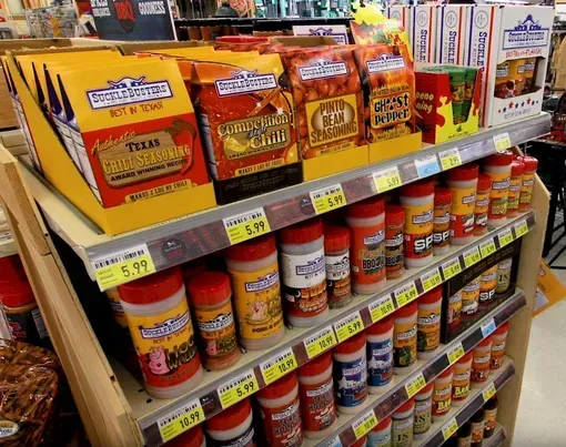 Grocery store shelf stocked with assorted canned soups and boxed mixes in orange and yellow packaging