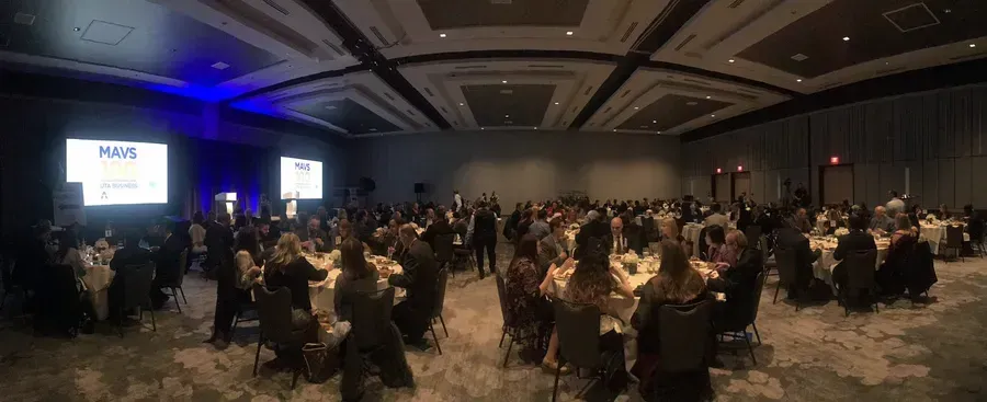 Conference banquet hall with seated attendees and a presentation screen at the front