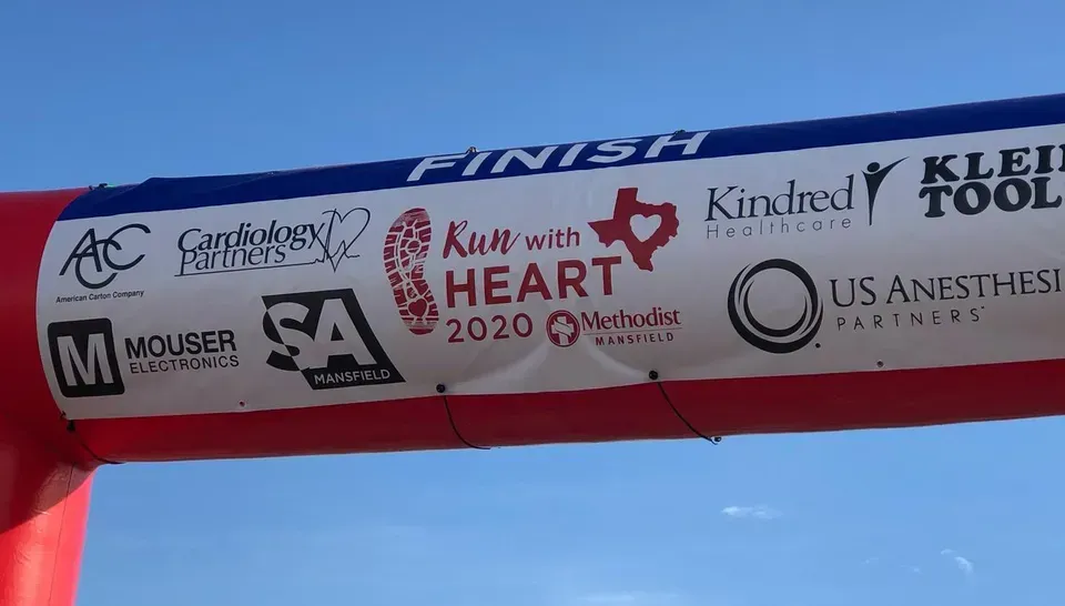 Sponsors' banner on a red inflatable arch against a blue sky, with logos and 