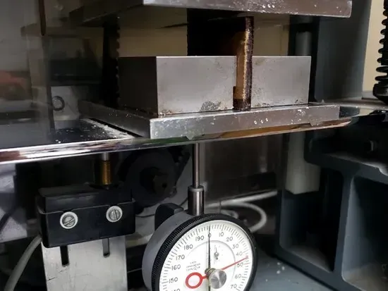 Dial indicator measuring a metal machine part in a workshop setup