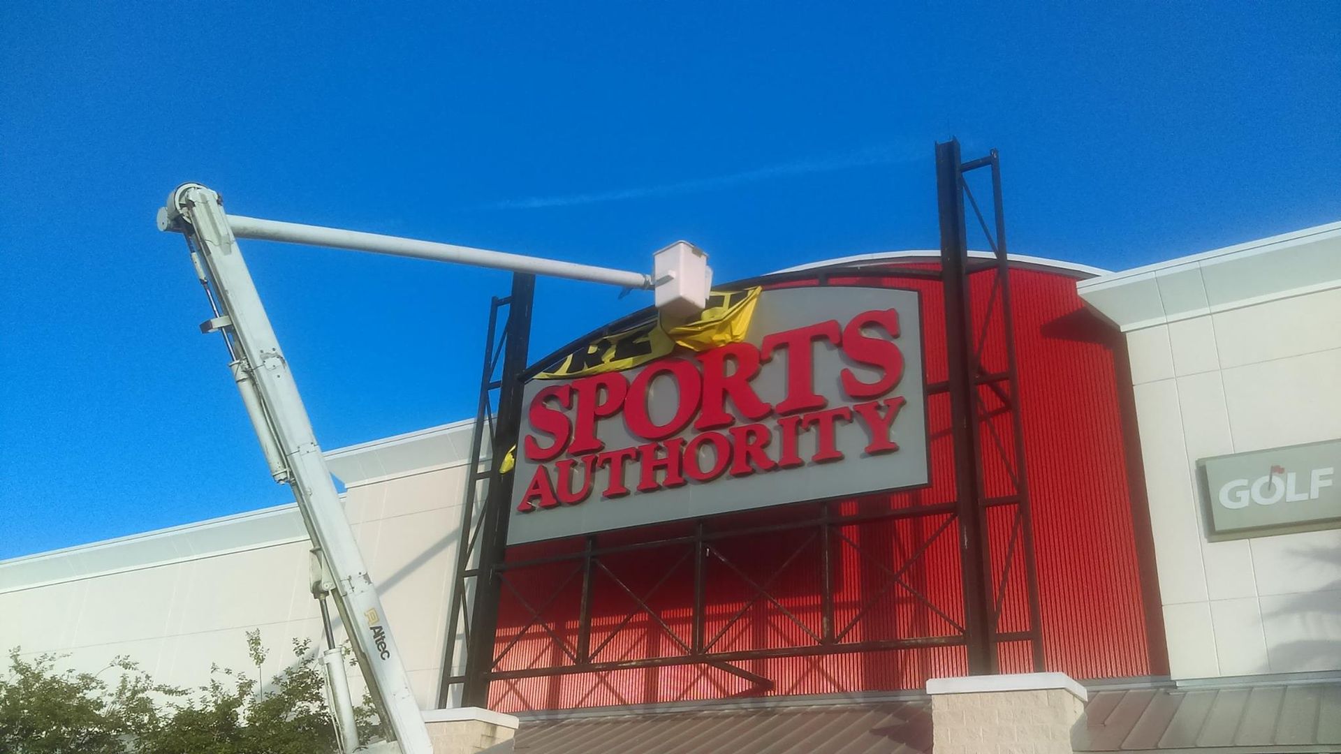 A sports authority sign is being installed on the side of a building