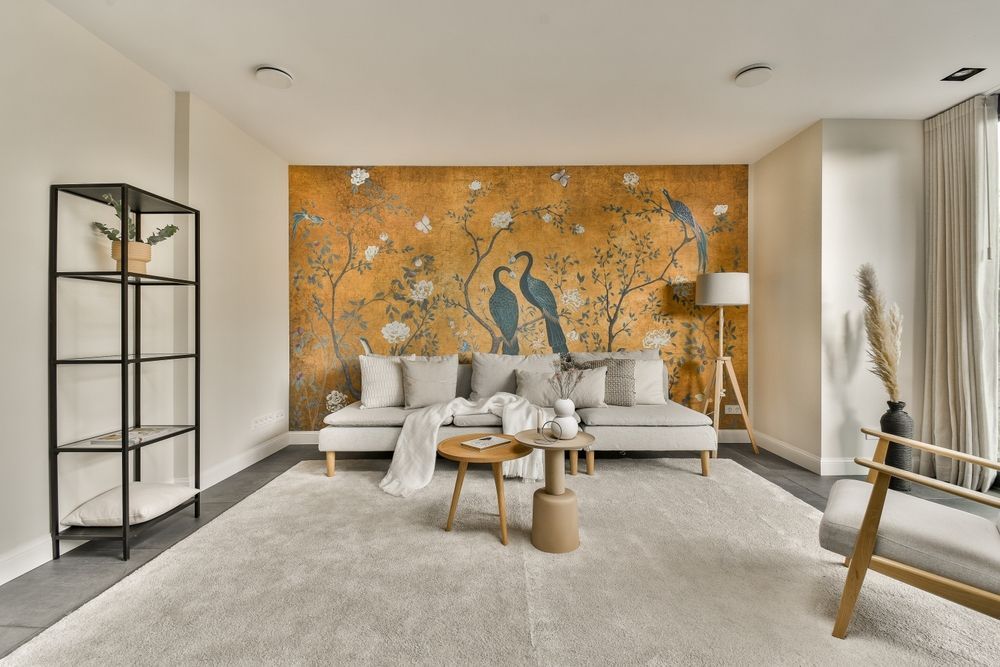 A living room with a couch , chairs , coffee tables and a large wall mural.