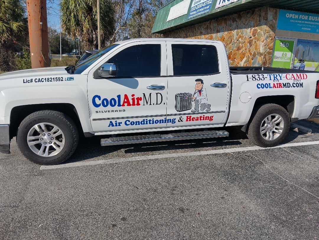 A white truck is parked in a parking lot in front of a building.