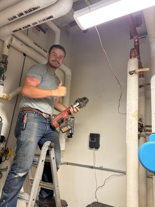 Man in blue shirt working on electrical wiring in a closet, using tools.