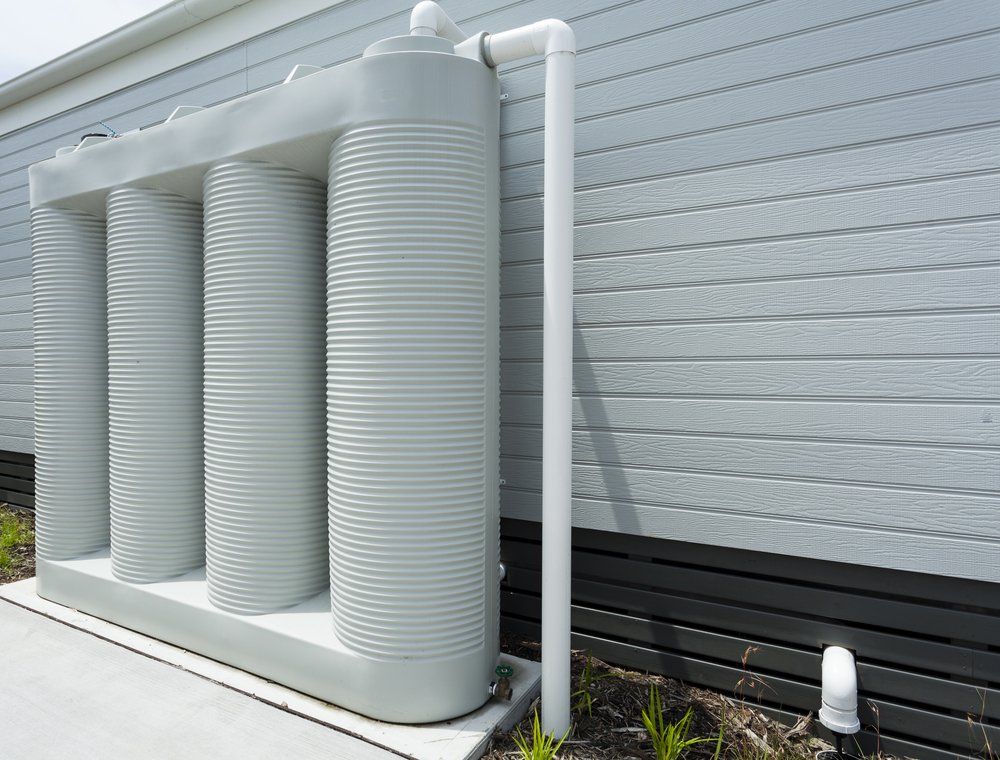 A White Water Tank is Attached to the Side of a House — Mid Richmond Plumbers & Suppliers in Coraki, NSW
