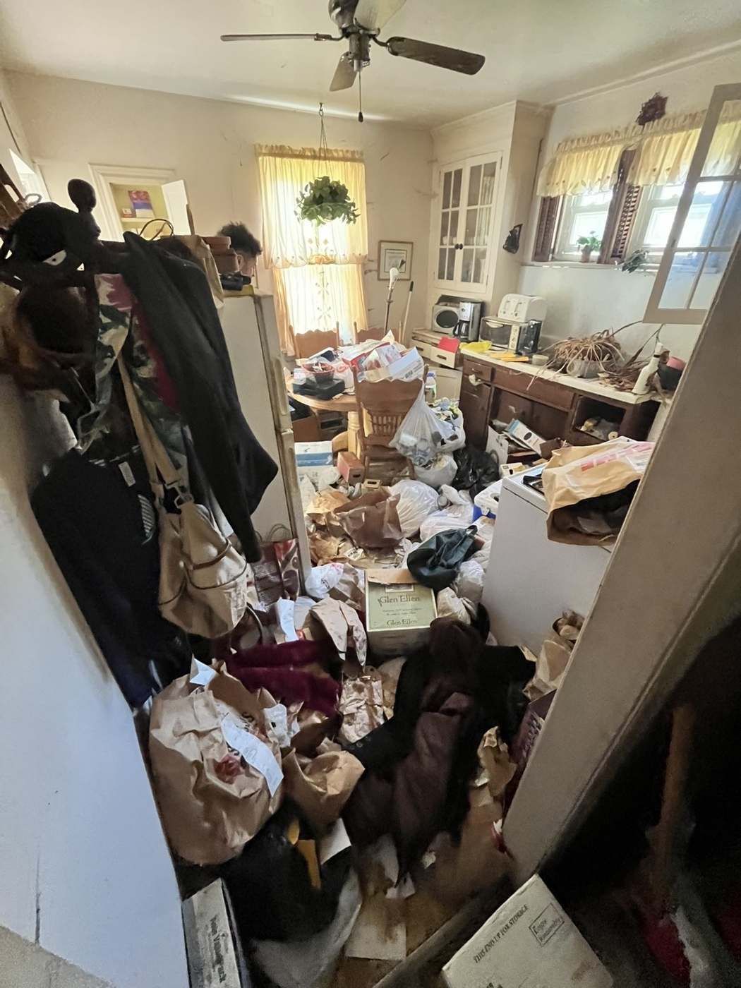 Cluttered kitchen and hallway full of bags and boxes before an estate cleanout