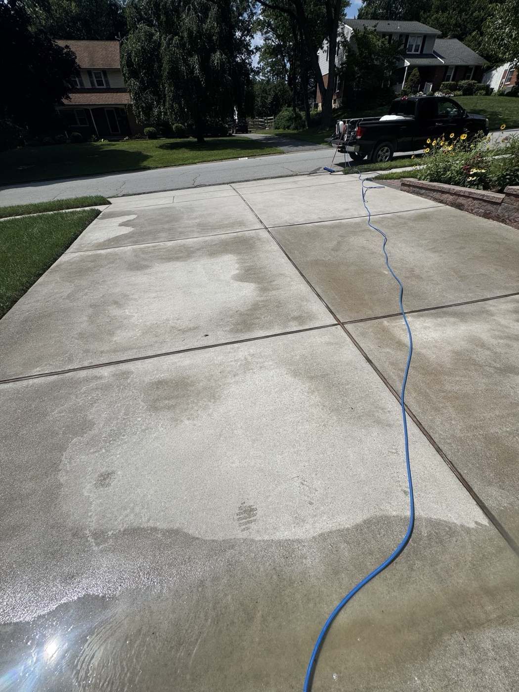 Driveway partway through pressure washing showing clean and dirty contrast