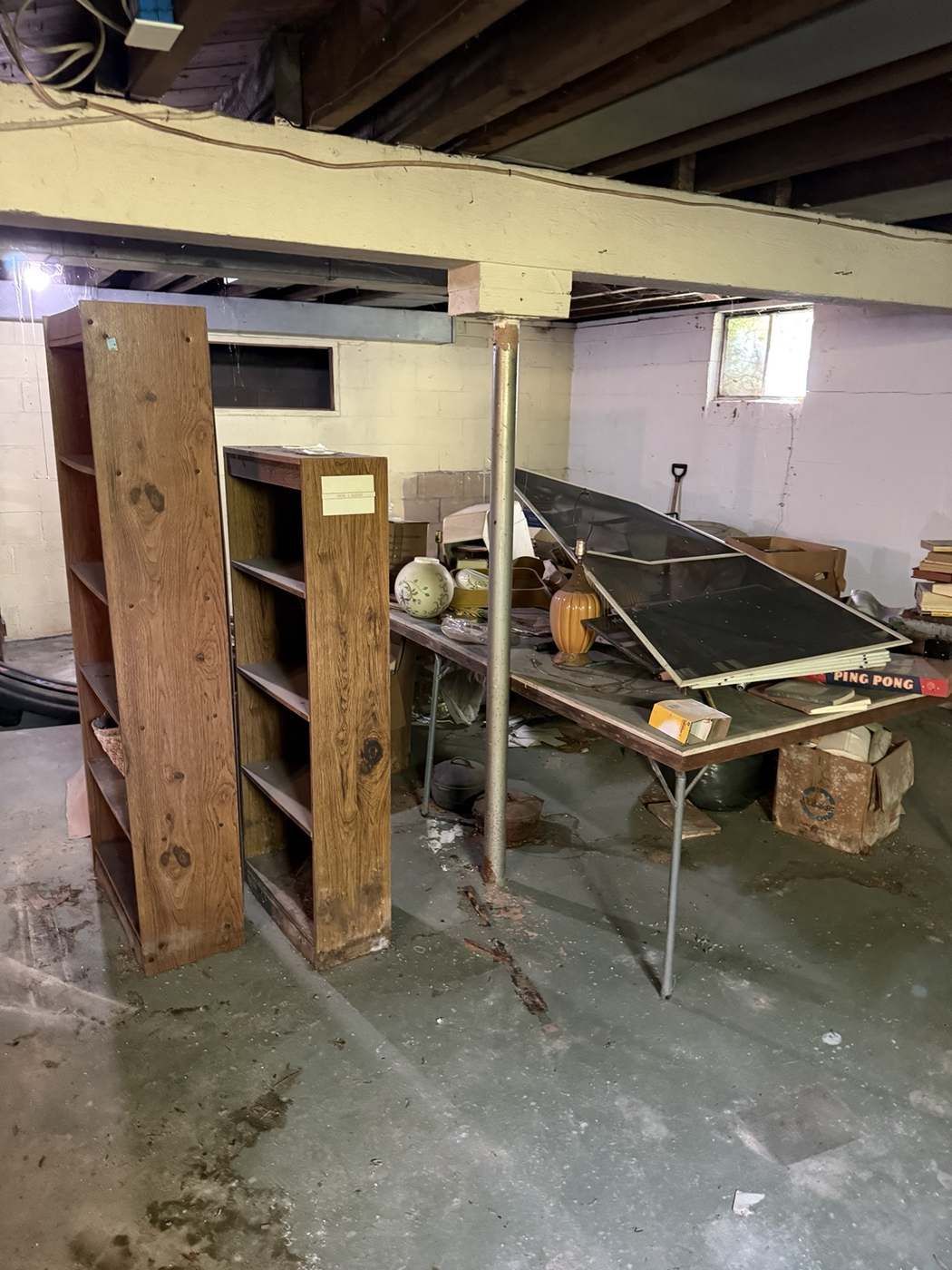 Cluttered basement full of furniture and shelving before cleanout