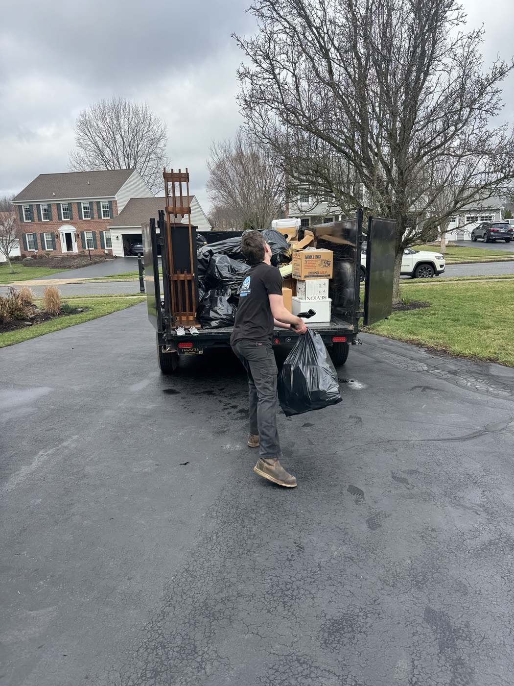 Technician loading bagged junk into a trailer during a junk removal job