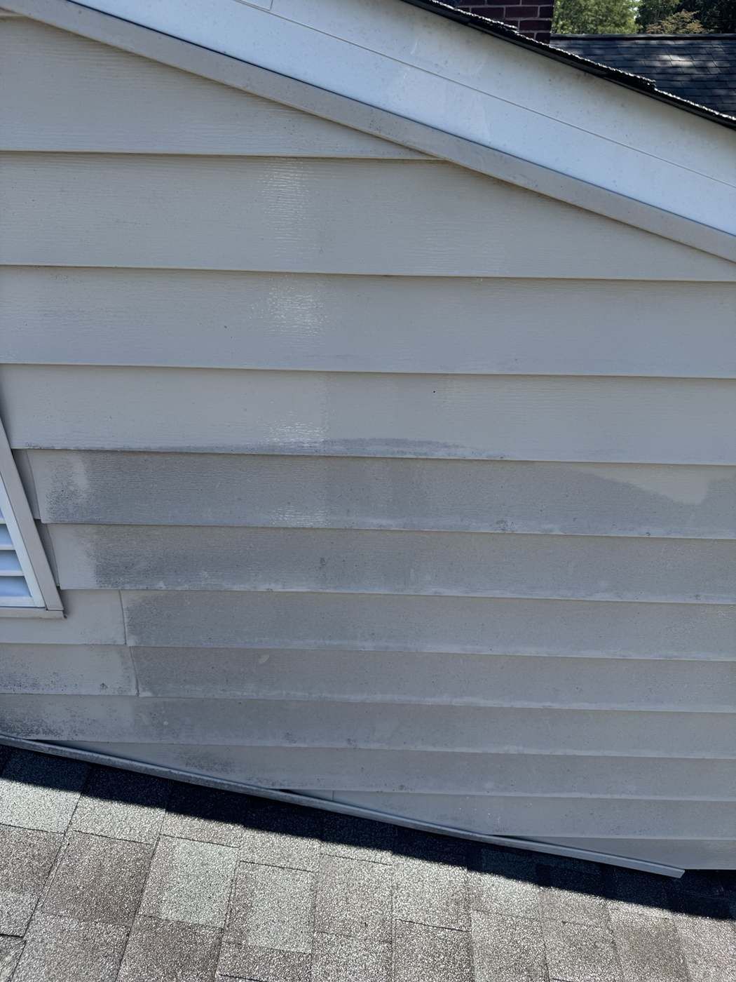 Close up of house siding showing clean and dirty contrast during soft washing
