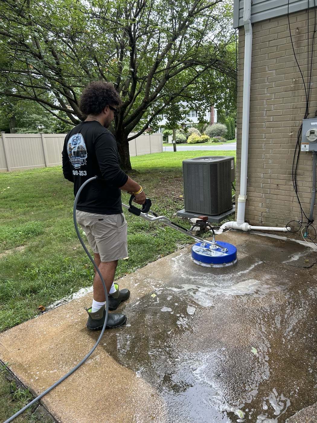 Technician surface cleaning a concrete patio near the house
