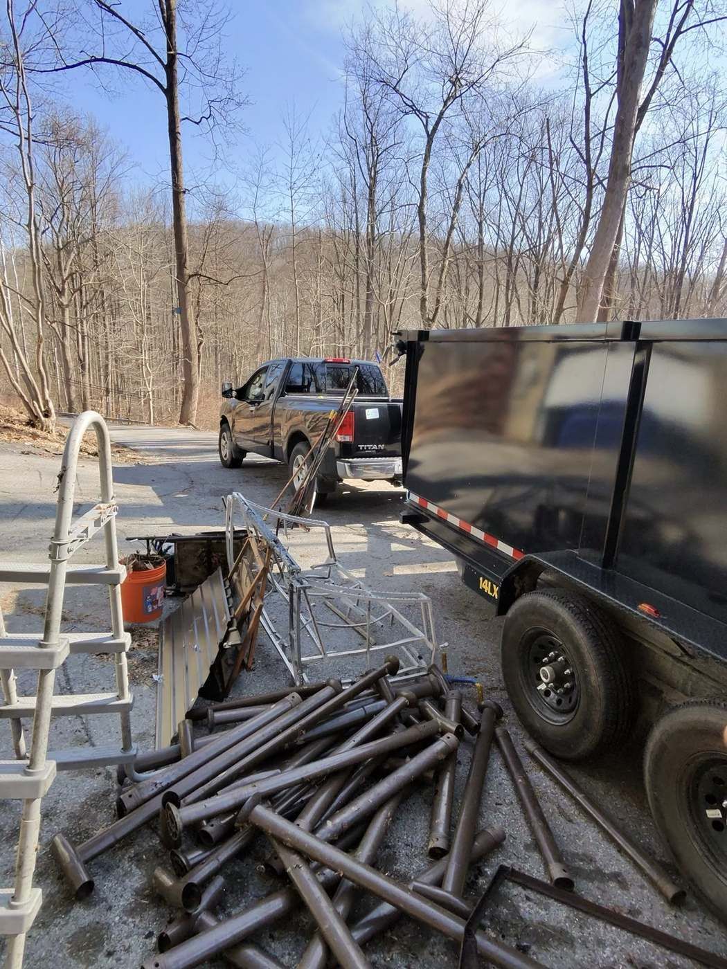 Metal debris and poles loaded for haul away next to trailer