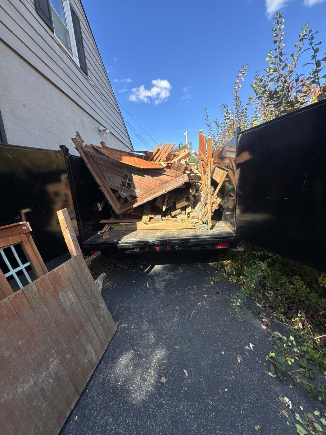 Wood debris and demolished shed loaded into trailer for junk removal