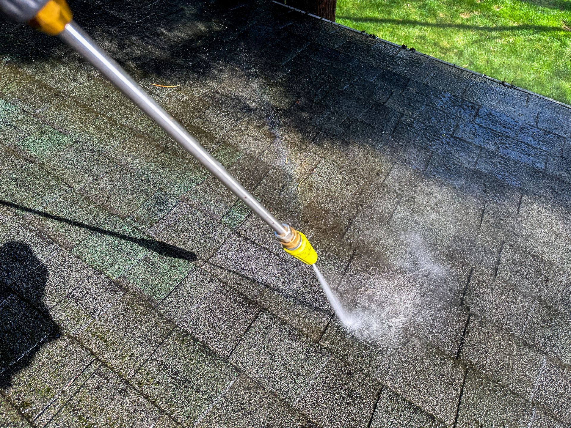 Pressure washing a mossy roof with a spray wand and water jet
