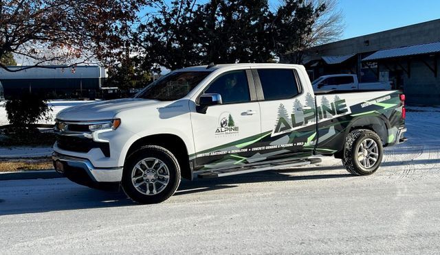 A white truck is parked in the snow in front of a building.