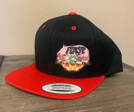 A black hat with a red brim is sitting on a wooden table.